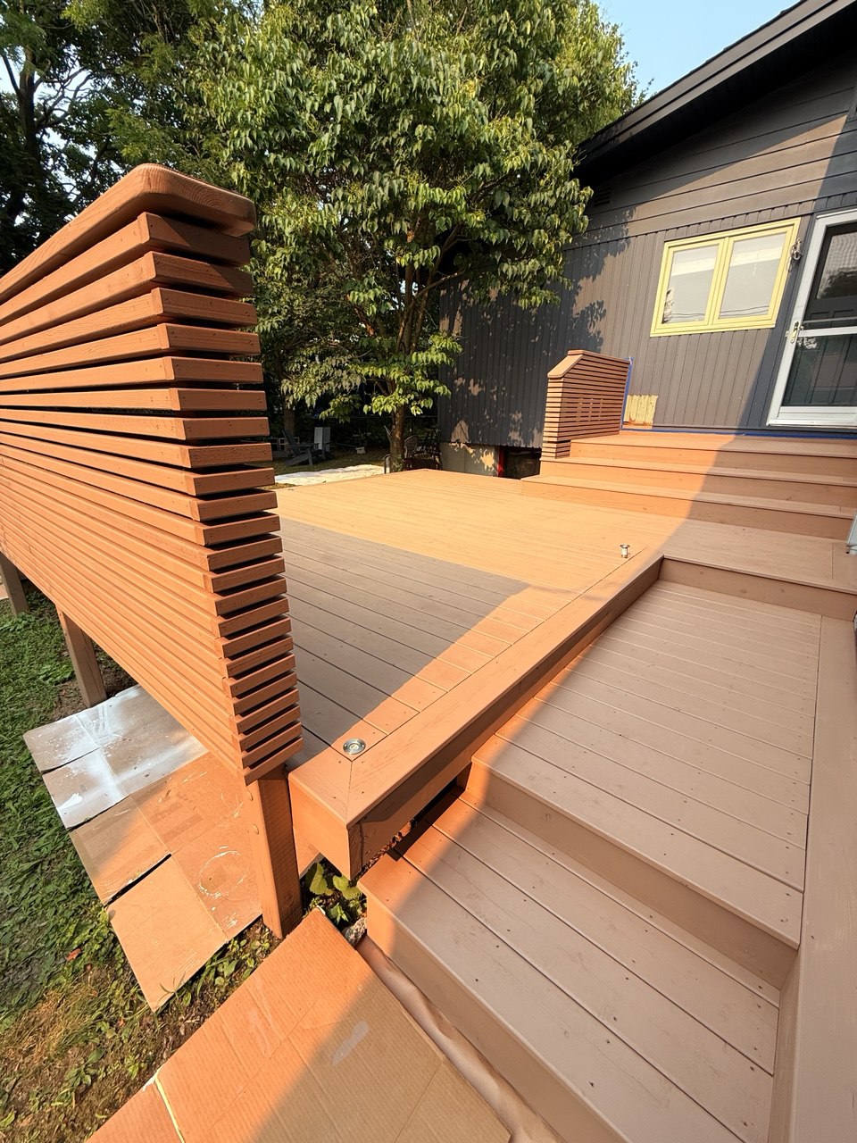 Completed deck renovation with freshly sanded and amber-stained boards and matching railing